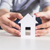 photo de mains entourant une maison en papier