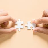 mains connectant deux pièces de puzzle sur une table