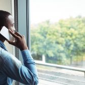 homme au téléphone regardant par la fenêtre