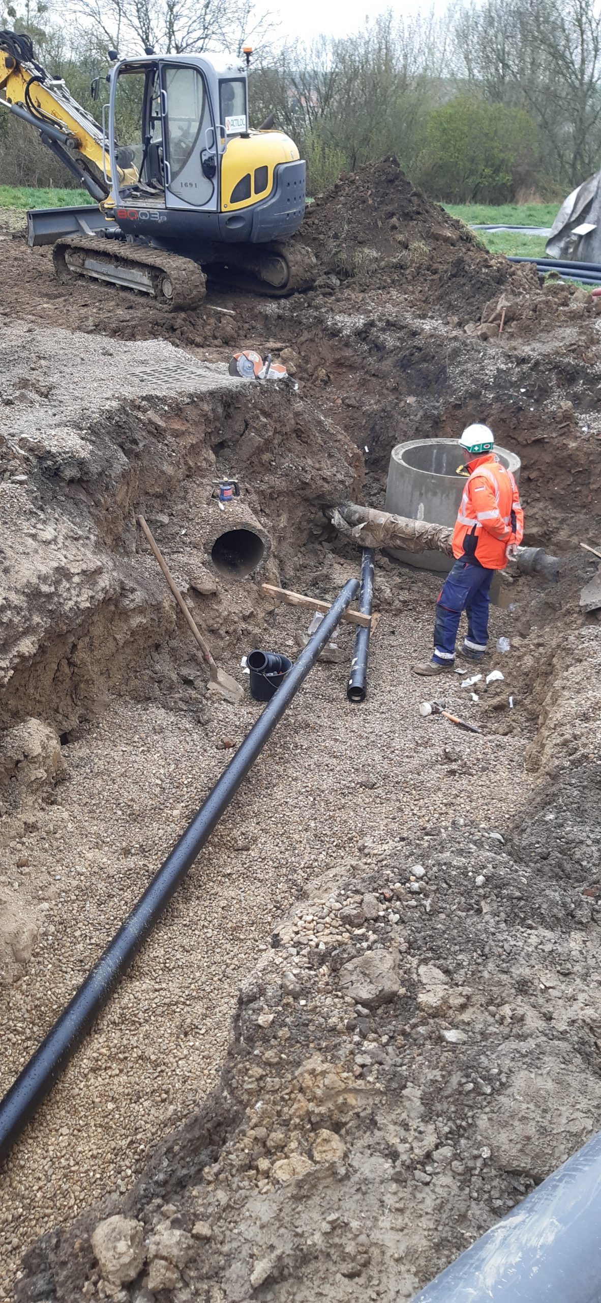 engin chantier et ouvriers en cours de pose de réseaux d'assainissement